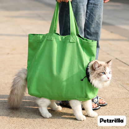 Cat walking with its paws through the leg openings of the green Petzrella cat carrier bag