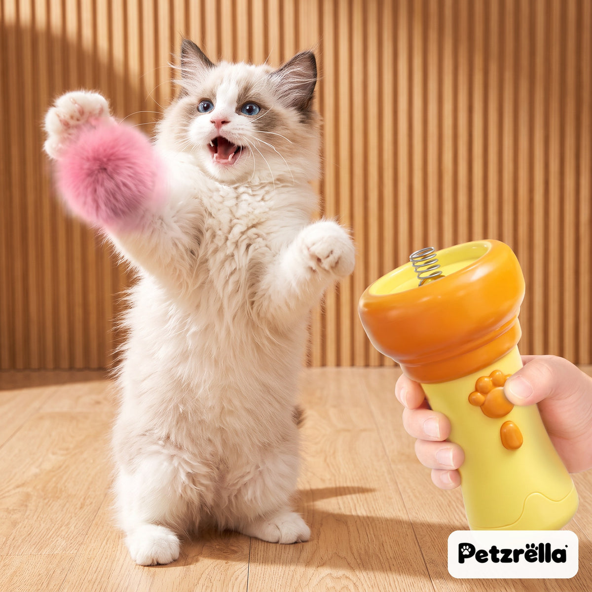 Petzrella interactive cat ball launcher in yellow with a fluffy kitten chasing a pink pompom
