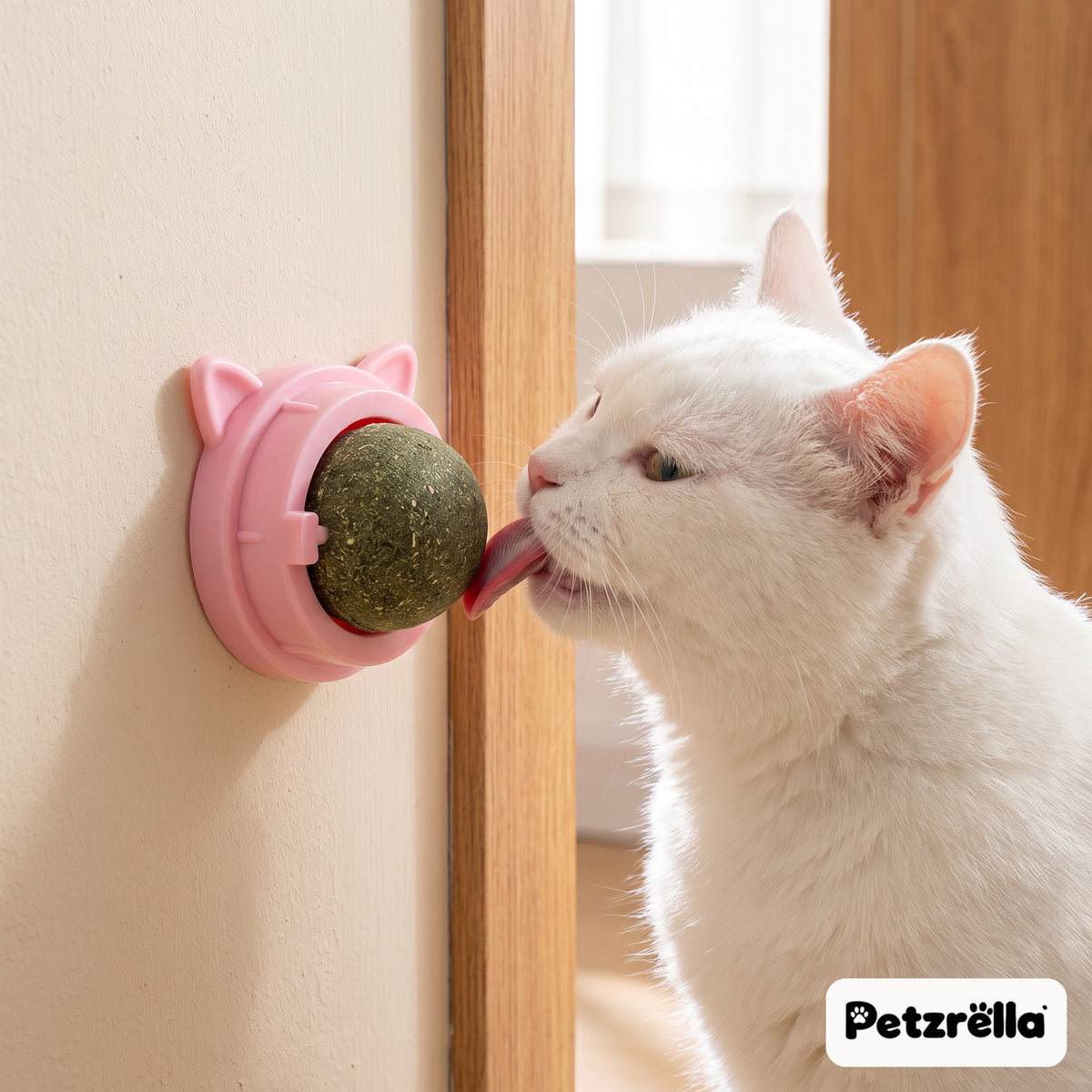 Petzrella pink catnip wall ball stuck to a wall and licked by a white cat at home