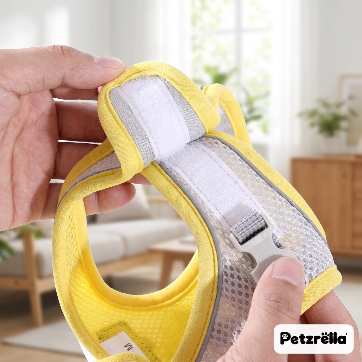 Petzrella yellow reflective padded dog harness held in hands, showing velcro and mesh